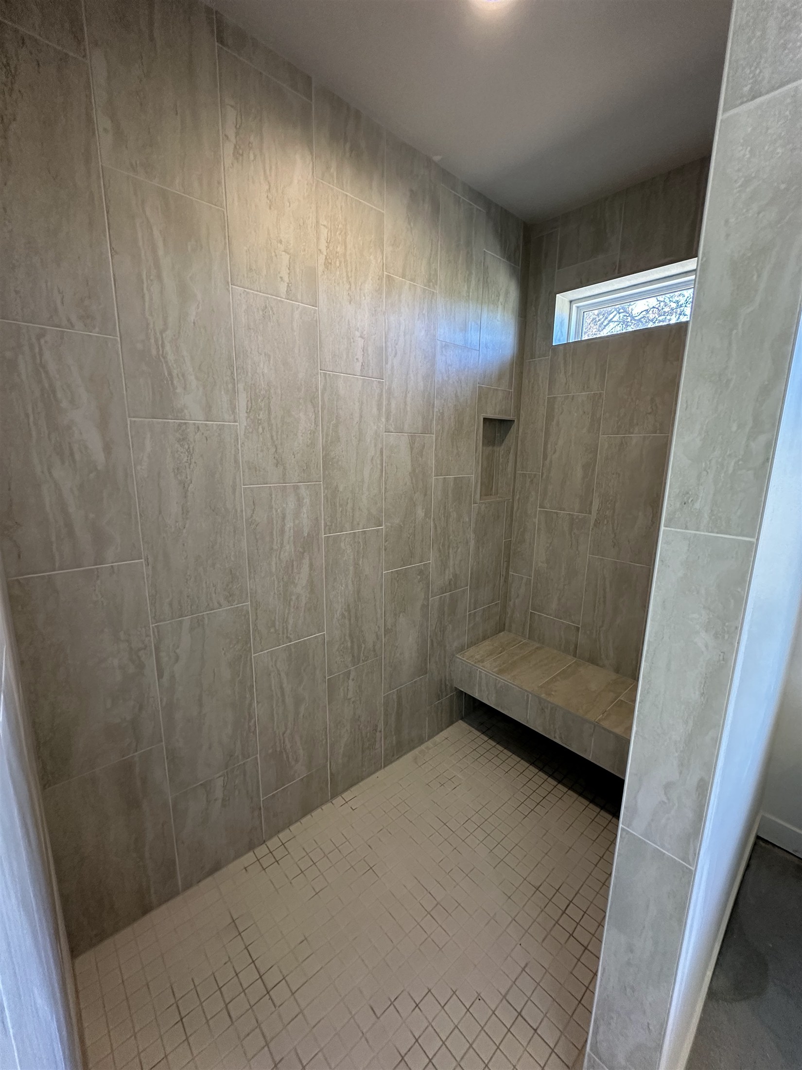 Textured shower walls & tile floor installed by Heartland Tile